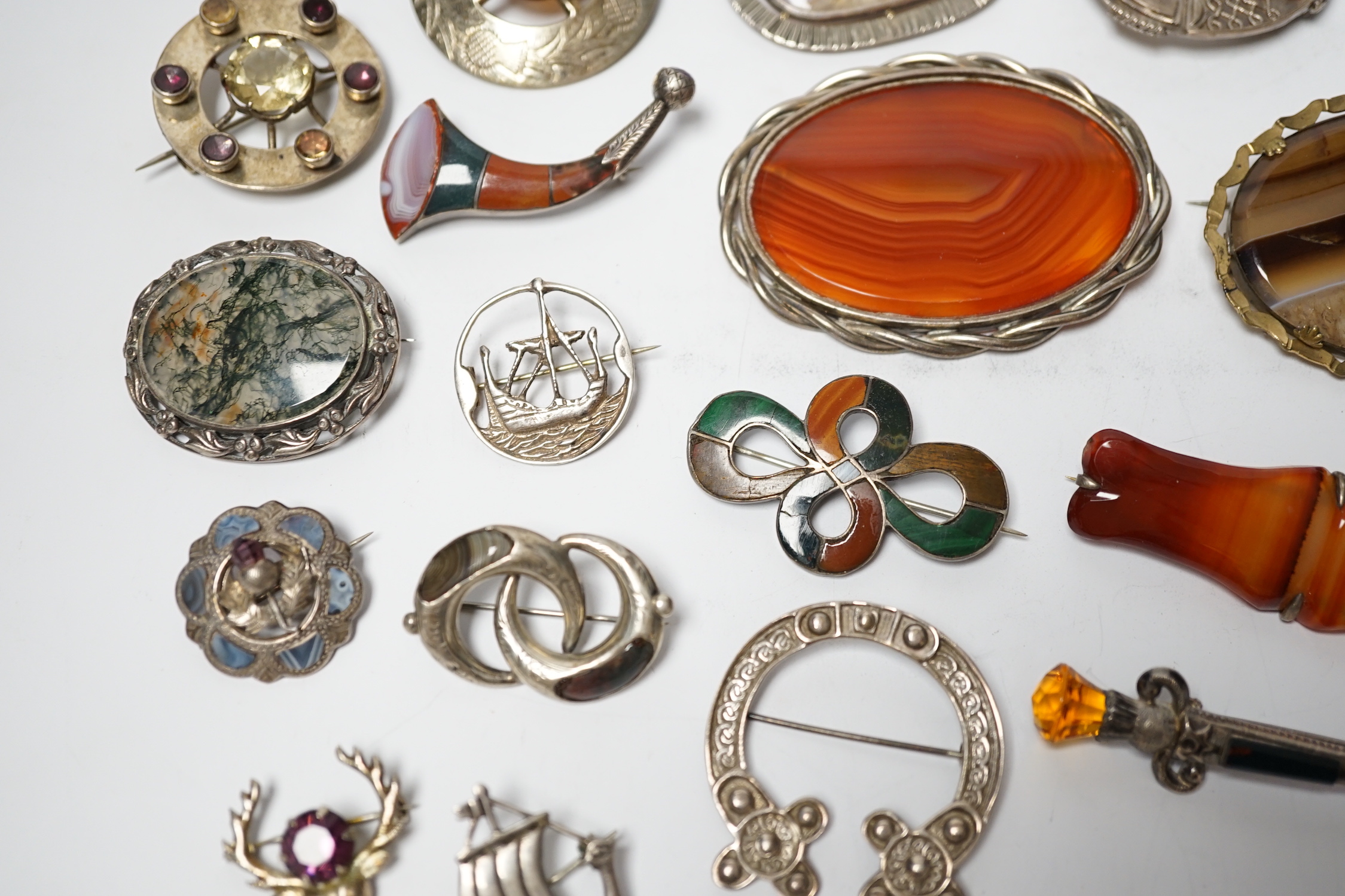 A small collection of mainly silver, sterling and white metal jewellery including Celtic brooches, Iona ship brooch, a Scottish hardstone set bugle brooch and other moss agate set and banded agate set items, largest broo